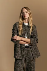 Sobrecamisa de corte relajado con estampado animal print, cuello camisero, cierre frontal con botones y bolsillos aplicados.