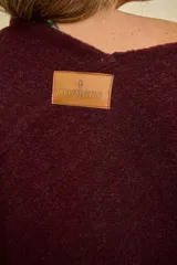 Ruana de lana color bordó con terminación de flecos en los extremos y diseño en picos en la espalda.