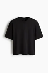 Remera negra de corte oversized y silueta holgada, confeccionada en punto liviano de algodón, con cuello redondo ribeteado y mangas cortas de hombros caídos.