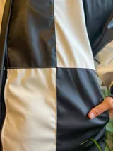 Campera con cierre frontal, diseño color block blanco y negro, cuello camisero y bolsillos laterales.