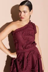 Top color bordó de un solo hombro, con volados decorativos en el escote y en el cuerpo de la prenda.