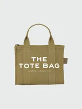 Bolso tipo tote de Marc Jacobs, confeccionado en lona resistente color beige. Presenta el logo estampado en contraste en el frente, doble asa superior y cierre superior con cremallera.