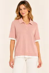 Remera polo de punto color rosa viejo, de manga corta con puños acanalados, cuello camisero y cartera con tres botones. Cuenta con un diseño superpuesto que deja ver una prenda interior blanca en el cuello, mangas y ruedo.