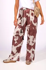 Pantalón con estampado de vaca en satén liviano de caída suave, cintura elastizada y cordón decorativo.