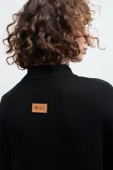 Camisa negra de tejido de punto acanalado, con cuello tipo polo y botones blancos.