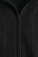 Campera deportiva de sherpa cálida y suave, color negro, con cuello elevado, cierre frontal y bolsillos laterales. Cuenta con corte holgado y elásticos en puños y bajo.