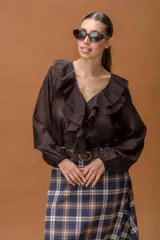 Camisa de color marrón con volados frontales, escote en V y mangas largas con puños ajustados.