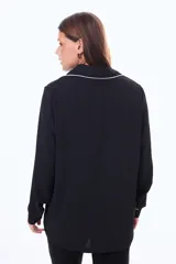 Camisa negra de manga larga con cuello estilo pijama y cierre frontal de botones. Presenta un vivo blanco en contraste que recorre el cuello, la tapeta de botones y los puños.