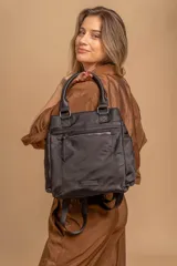 Cartera mochila de diseño funcional en color negro, confeccionada en nylon impermeable. Cuenta con un compartimento principal con cierre, un bolsillo frontal con cierre, asas superiores de mano y correas ajustables para llevar en la espalda. Incluye un parche con el logo de la marca en la parte inferior.