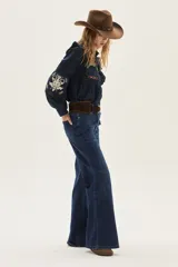 Blusa azul marino de algodón con volados en los hombros, mangas largas abullonadas y detalles de bordados florales y geométricos en el pecho y las mangas.