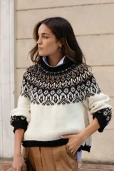 Sweater de lana con diseño de jacquard en la parte superior, cuello redondo, mangas largas y puños acanalados. Presenta un corte holgado con tajos laterales y un diseño ligeramente más corto en la parte delantera.