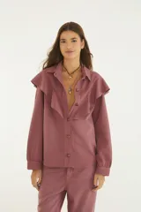 Camisa de denim color rosa viejo, con cuello clásico, volados grandes en el delantero, cierre frontal con botones y mangas largas con puños.