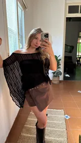 Capa de hilo negra con diseño de hombros descubiertos, mangas anchas y acampanadas, y textura de rayas verticales.