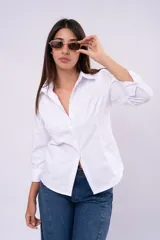 Camisa blanca de corte clásico con cuello camisero, cierre frontal de botones y mangas largas con puños.