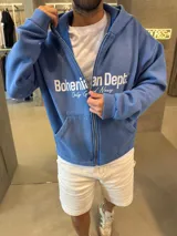 Campera con cierre frontal, confeccionada en algodón premium, con corte boxy y capucha. Presenta estampado frontal con la marca Bohemian Dept.