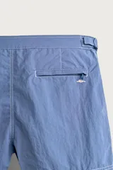 Short de baño azul con pespuntes en contraste, bolsillos frontales, cintura ajustable con trabillas laterales y cierre frontal.