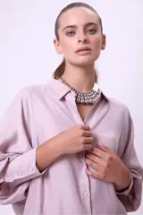Camisa de cupro color lila de calce oversize, con cuello camisero y botones frontales a tono. Posee mangas largas con volumen y puños definidos.