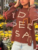 Sweater marrón de punto jersey de algodón, con diseño oversize, cuello redondo y bordados artesanales en relieve de colores con hilos de lúrex y flecos decorativos en las mangas.