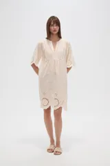 Vestido corto color crema, con escote en V y mangas 3/4. Presenta detalles de bordado inglés (broderie) en el canesú superior y en el ruedo inferior.