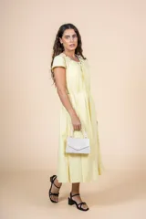 Vestido midi amarillo pálido, de corte recto y manga corta, con escote redondo con detalle de bordado floral. Tiene lazo ajustable en la cintura.