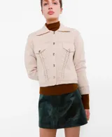 Chaqueta de punto color beige, de corte corto, con cuello camisero, bolsillos frontales con solapa y botones metálicos.