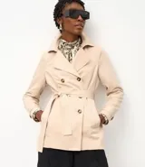 Buzo femenino modelo trench coat, confeccionado en poliéster con detalles acetinados. Posee cuello solapa, cierre delantero con 6 botones matizados y lazo con faixa pespontada.