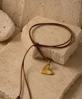 Gargantilla de cordón de cuero marrón con dije de corazón en metal dorado de acabado mate.