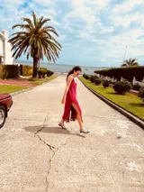 Vestido de fiesta fucsia con escote y espalda de cuero, tajos laterales con hilo metálico y terminación con flecos.