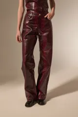 Pantalon de corte recto con diseño de estampado de piel de serpiente, confeccionado en cuero sintético (PU). Presenta bolsillos laterales y cierre frontal con botón.