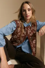 Chaleco tejido de punto con diseño floral ornamental, de silueta recta y cierre frontal con botones. Presenta una estética romántica y sofisticada, ideal para superponer sobre otras prendas.