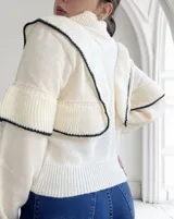 Cárdigan tejido color crudo con cuello redondo, cierre frontal con botones y mangas abullonadas con puños acanalados y detalle de rayas negras.