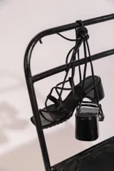 Sandalias de tacón color negro con tiras finas y cordones para atar al tobillo.