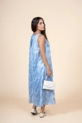 Vestido midi de corte amplio y silueta recta, con cuello redondo y diseño sin mangas. Presenta un estampado tipo tie-dye en tonos azules y blancos, confeccionado en una mezcla de algodón y poliéster.