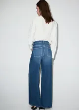 Jeans de tiro medio con diseño wide leg, cintura cruzada y cierre frontal asimétrico con cremallera y botones. Cuenta con cinco bolsillos y presillas para cinto.