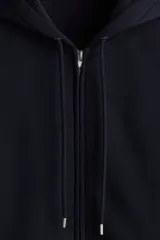 Campera con capucha de felpa color azul marino, con interior cepillado suave. Presenta hombros caídos, cierre frontal, bolsillos canguro delanteros y puños y bajo en punto acanalado. Corte holgado.