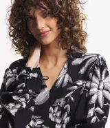 Vestido corto de viscosa con estampado floral en blanco y negro, escote en V, mangas largas con lazo en los puños y volados en el ruedo.