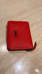 Billetera de cuero de pelo con estampado animal print tipo vaca en blanco y negro. Cuenta con cierre perimetral y tirador de cuero con detalle metálico.