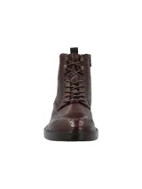 Botín de cuero estilo brogue con cordones, acabado en tono marrón oscuro. Presenta detalles de perforaciones decorativas en la puntera y laterales, con suela de cuero y diseño clásico de caña media.