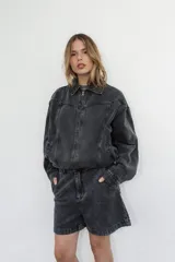 Campera de denim color negro con efecto lavado, corte semi oversize, cierre frontal completo, cuello camisero y bolsillos laterales.