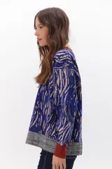 Sweater de punto con estampado animal print en tonos marrones, negros y blancos. Tiene cuello redondo, puños y bajo acanalados en color marrón y gris.