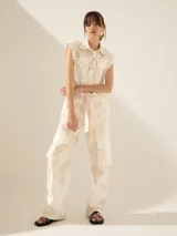 Mono largo color crudo con estampado abstracto, corte holgado, cuello camisero, cierre frontal con botones, sin mangas, cinturón de lazo y bolsillos cargo.