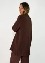 Sweater de punto color beige, de corte holgado y diseño oversize. Presenta cuello alto y puños con detalle de tejido trenzado, al igual que en el ruedo inferior.