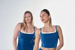 Conjunto deportivo compuesto por un top de tirantes finos con detalle de borde en contraste y calzas largas ajustadas, ambos en color azul petróleo.