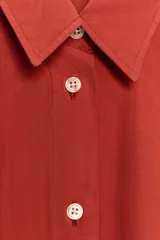 Camisa de corte oversize confeccionada en popelín de algodón, con cuello solapa, manga larga con puños y cierre frontal de botones.