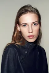 Camisa de denim azul oscuro, de corte cuadrado y manga ancha acampanada. Presenta cuello mao y cierre asimétrico con botones a presión en el frente.