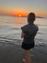 Chaleco sin mangas de gabardina con acabado foil (efecto satinado/brillante), color gris oscuro o negro. Presenta cuello alto y pespuntes contrastantes visibles en el frente y hombros.