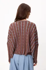 Sweater de punto con diseño de rayas verticales en relieve y textura trenzada, color terracota y beige. Presenta cuello redondo, corte holgado y diseño cropped.
