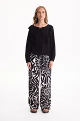 Blusa de viscosa color blanco con escote en V y cordón ajustable, mangas largas y volados decorativos en los hombros.