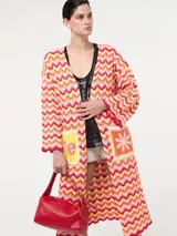 Saco tejido largo con diseño de ondas en tonos naranja, rosa, amarillo y blanco. Tiene bolsillos delanteros y mangas largas acampanadas.