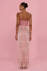 Vestido largo rosado con tirantes finos, falda de capas con flecos brillantes y gran aplique floral bordado en el pecho.